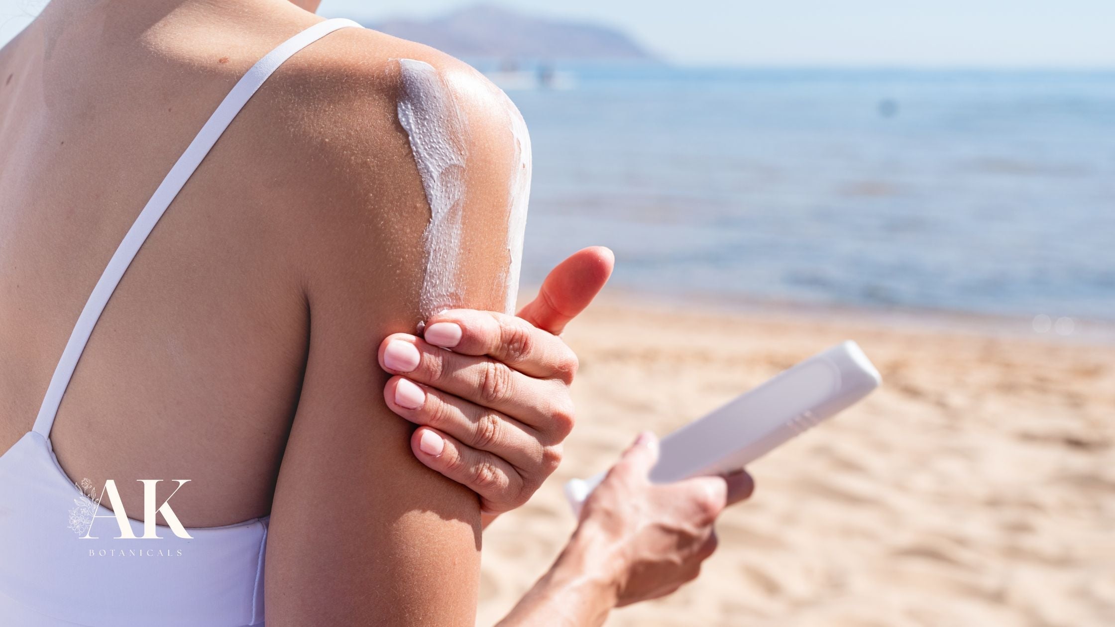 Woman applying sunscreen on shoulder at the beach to prevent sun damage and actinic keratosis – AK Botanicals skincare awareness.
